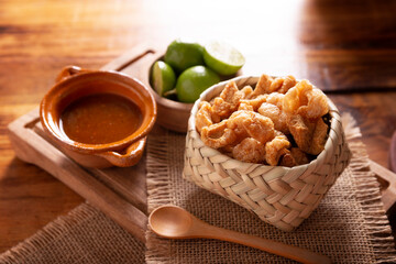 Chicharrones. Deep fried pork rinds, crispy pork skin pieces, traditional mexican ingredient or snack served with lemon juice and red hot chili sauce.