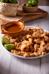 Chicharrones. Deep fried pork rinds, crispy pork skin pieces, traditional mexican ingredient or snack served with lemon juice and red hot chili sauce.