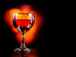 Glass or red wine, dark background with fire color light painting effect. Alcohol product for a special occasion.