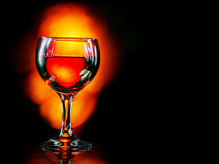 Glass or red wine, dark background with fire color light painting effect. Alcohol product for a special occasion.