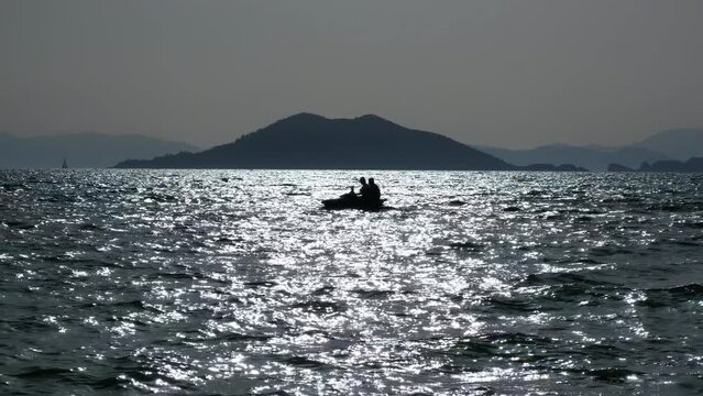 Scooter in the sea. Two people on a jet ski in the sea at sunset against the backdrop of the islands.