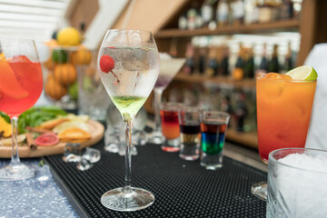 a transparent cocktail with lime and cherry stands on the bar