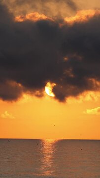 Vertical video of golden orange sunrise over ocean waves.