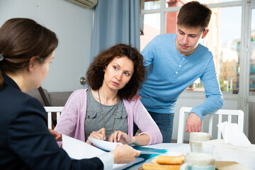 Fototapeta premium Positive woman with teenager boy discussing documents with financial adviser