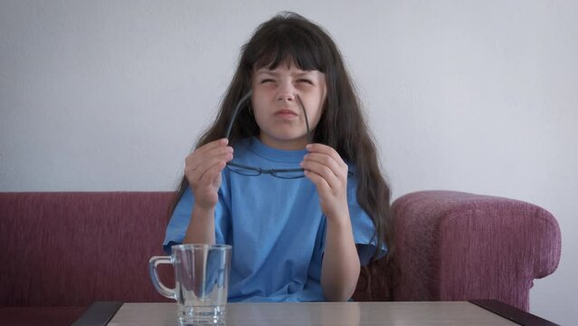 Child vision problems with squinting eyes. A stressed child with strained eyes wear glasses for better vision in the flat.