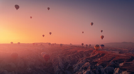 Amazing Panoramic view sunrise rocky landscape in Cappadocia with colorful hot air balloon deep canyons, valleys. Concept banner travel Turkey - obrazy, fototapety, plakaty