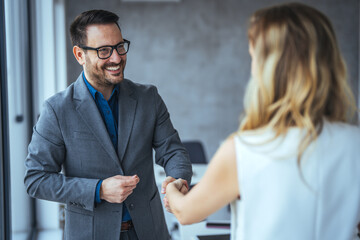 Business people shaking hands after successful meeting. Businessman And Businesswoman Shaking Hands In Office. Businessman shaking hands with his female partner celebrating successful teamwork. - obrazy, fototapety, plakaty