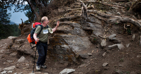 A trekker waving hello to a trail side goat in Nepal