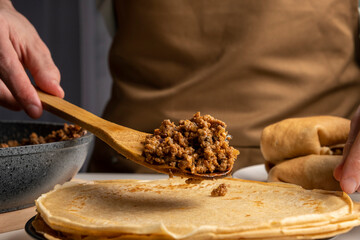 Russian traditional dish. Chif making pancakes with filling. Pancakes with meat and mushrooms. Maslenitsa.