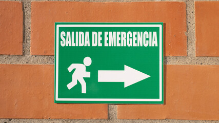 Green emergency exit sign in Spanish