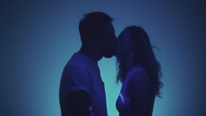 A young couple is kissing in the studio. A man and a woman make a kiss with their lips, a laser shines. A guy and a girl are hugging, in love. Honeymoon after the wedding, prelude before sex - Powered by Adobe