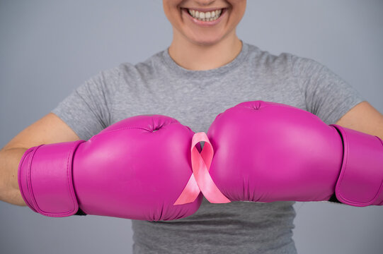 Close-up of women's boxing gloves and pink ribbon. 
