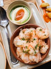 shrimp tapas with patatas bravas and a dipping sauce on a table in a cafe