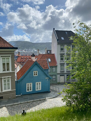 blue house with terracotta roof in the village on a cobblestone street with clouds in the sky and mountains in the background