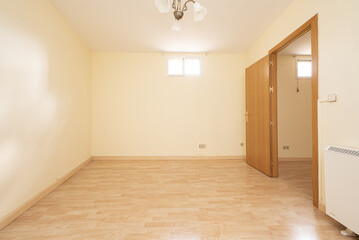 Empty living room with light yellow walls, light wooden floor, electric heater, oak wooden door,...