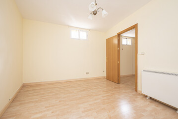 Empty living room with light yellow walls, light wooden floor, electric heater, oak wooden door,...