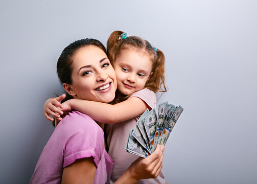Smiling mother and happy cute daughter hugging and showing dollars. Happy winning family. Closeup portrait