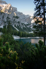The beautiful Lago di Braies seen from behind the trees at sunrise, in the Dolomites, Italy