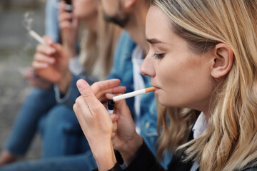 People smoking cigarettes at public place outdoors, closeup