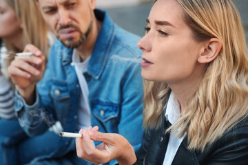 People smoking cigarettes at public place outdoors, closeup