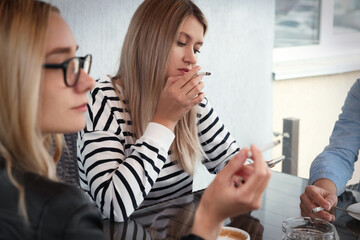 Women smoking cigarette at table in outdoor cafe
