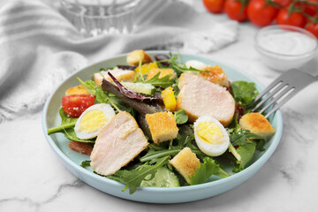 Delicious salad with croutons, chicken and eggs served on white marble table