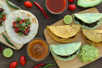 Delicious tacos and ingredients on wooden table, flat lay. Mexican food