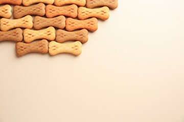 Bone shaped dog cookies on beige background, flat lay. Space for text