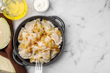 Cooked dumplings (varenyky) with tasty filling and fried onions on white marble table, flat lay. Space for text