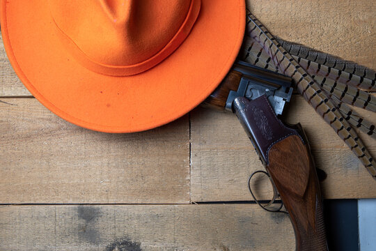 hunting lay flat with an orange hat, shotgun and pheasant feathers