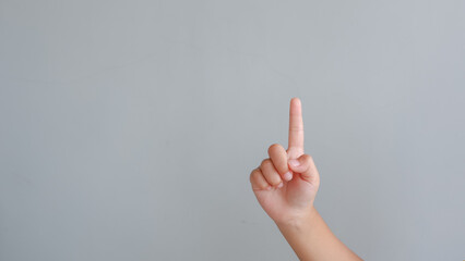 Hand gesture pointing up, isolated on grey background, young female hand closeup. counting one concept.