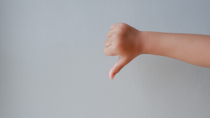 child's thumb down gesture dislike isolated on grey background.