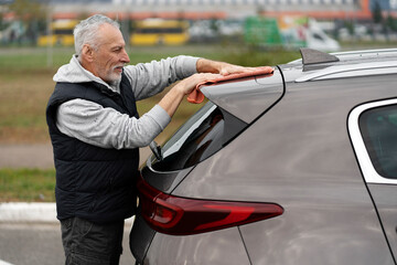 Side portrait handsome elderly man in casual wear, cleaning car in the self-service car wash station