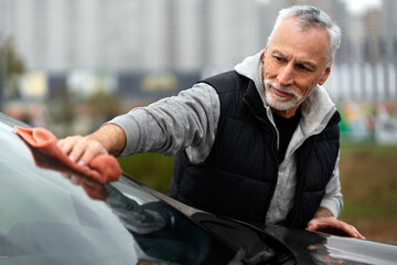 Fototapeta premium Car detailing. Caucasian senior man using microfiber cloth, polishes the car. Auto service and wash
