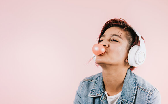Portrait of hispanic young woman with colored hair chewing gum and headphones listening music in Mexico Latin America