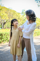 Happy cute little Asian girl or granddaughter having great time with her grandmother in park.