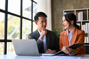 Two Asian businesswoman and businessman discussing and working on their project together