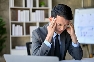 Stressed Asian businessman at his desk, worried about his business's financial investment