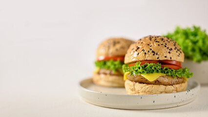 Tasty beef burgers with fresh vegetables and cheese on minimal ceramic plate, white background