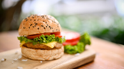 Close-up image of a tasty beef burger with fresh vegetables on wooden tray