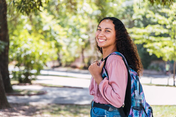 Successful latin student woman smiling in the park. Post-secondary education. 