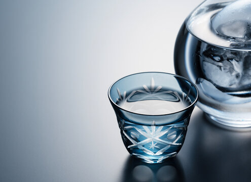 Sake poured into a faceted glass against a black background.