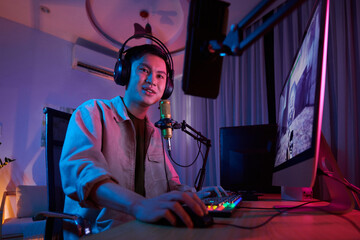Positive teenage videogamer playing computer game in neon bedroom at night © DragonImages