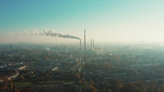 Drone shot at a power plant that generates electricity and useful heat. Gray steam comes out of tall chimneys in the city center. Gdansk. Poland. 