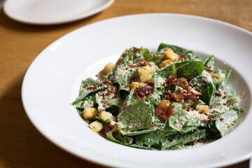 Caesar Salad on white plate on the wood table in restaurant