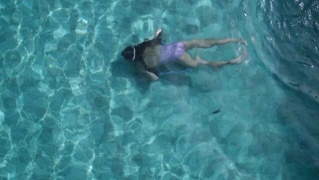 A happy little girl in scuba goggles is swimming underwater in the pool. Healthy lifestyle, water sports, outdoor adventures, family holidays with a child, summer holidays.