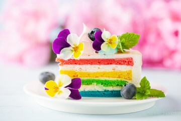 Delicious rainbow cake on plate on table on blue wooden background