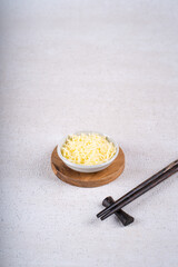 Grated cheese in white bowl on white concrete. Healthy food.