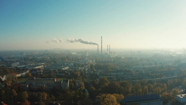 Drone shot at a power plant that generates electricity and useful heat. Gray steam comes out of tall chimneys in the city center. Gdansk. Poland. 