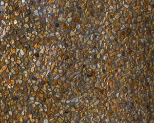 Yellow concrete wall texture with small rocks.